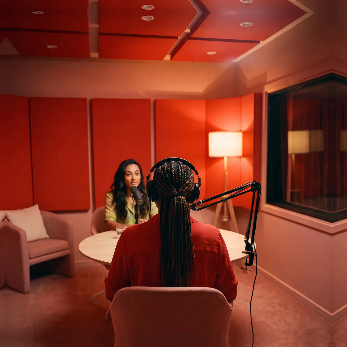 A podcast presenter in headphones facing a guest, from behind
